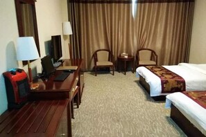 Ein Hotelzimmer mit Schreibtisch, zwei Stühlen, einem Bett und einem kleinen Tisch.