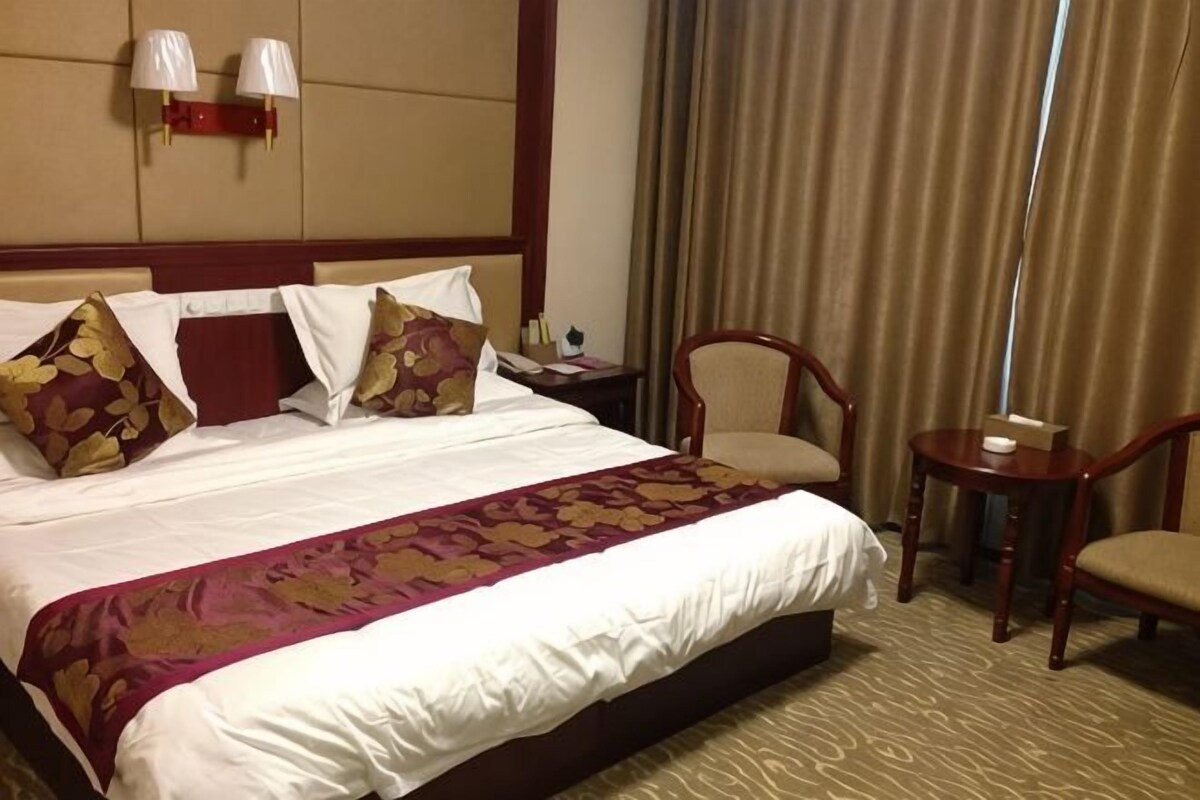 Ein Hotelzimmer mit einem großen Bett, einem Nachttisch, einem Sessel und einem kleinen Tisch.