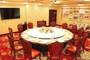 Une salle de conférence avec une table ronde, des chaises à revêtement rouge et un arrangement floral en guise de décoration centrale.