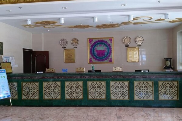 A reception desk with a green patterned counter, a clock, and framed certificates on the wall.