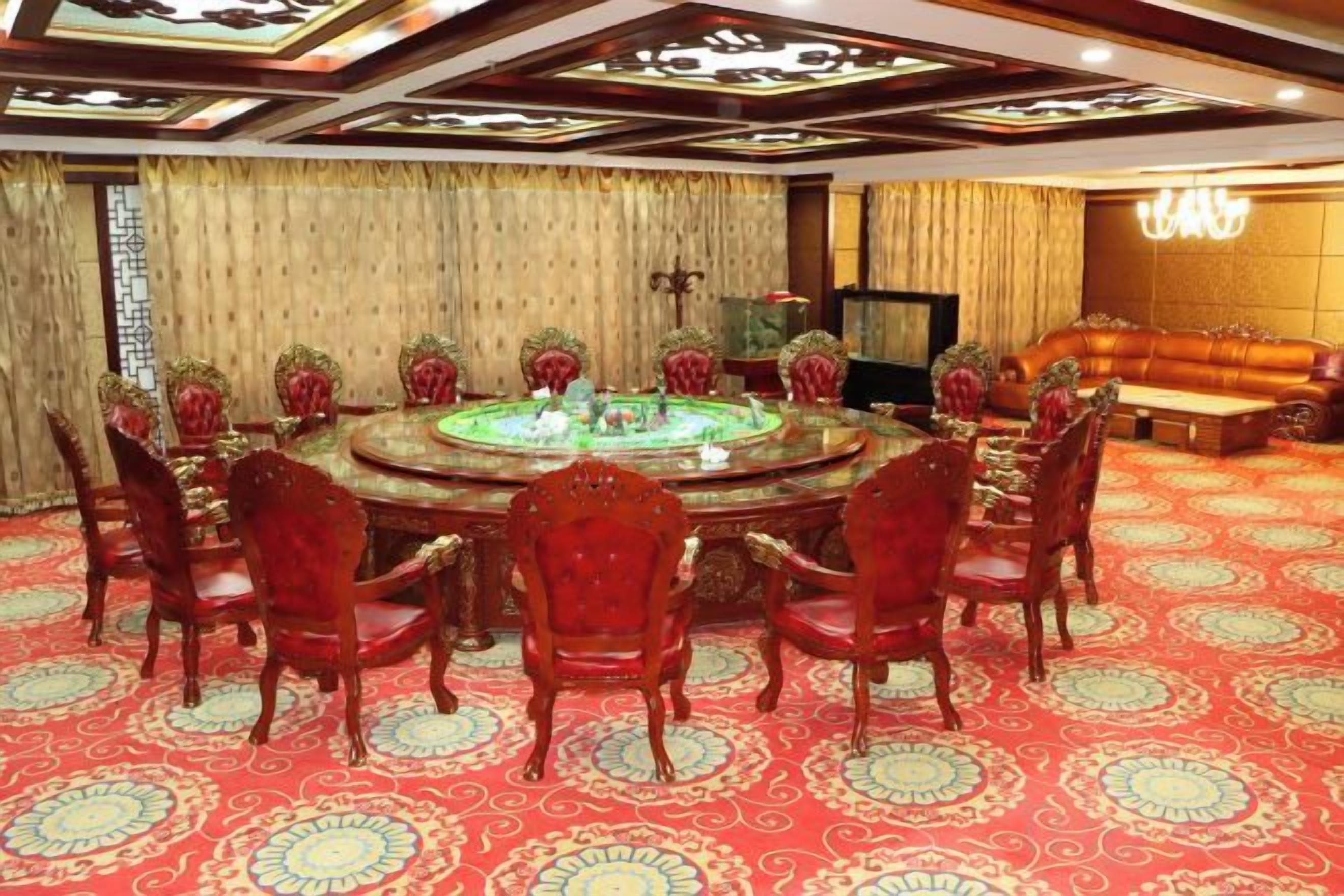 A conference room with a round table, red chairs, and a patterned carpet.