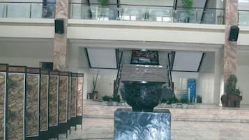 A lobby with a marble floor, a large black sculpture, and a staircase leading to an upper level.