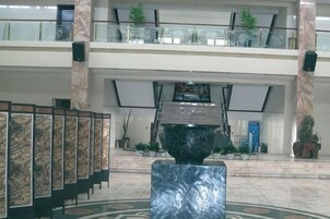 Un vestíbulo con piso de mármol, una gran escultura negra y una escalera que conduce a un nivel superior.