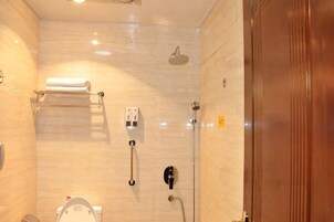 Un baño con inodoro, toallero, ducha y puerta de madera.