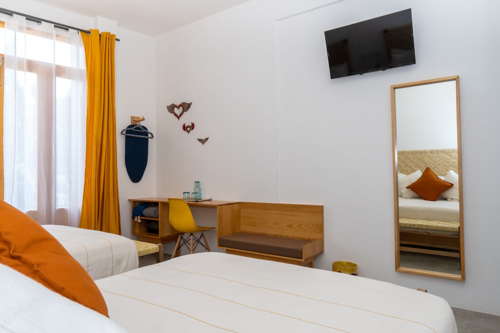 A hotel room with a bed, a desk, a chair, a TV, and a mirror.