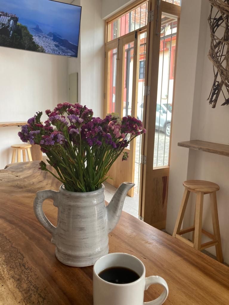 A wooden table with a white ceramic pitcher and a white mug containing a beverage.