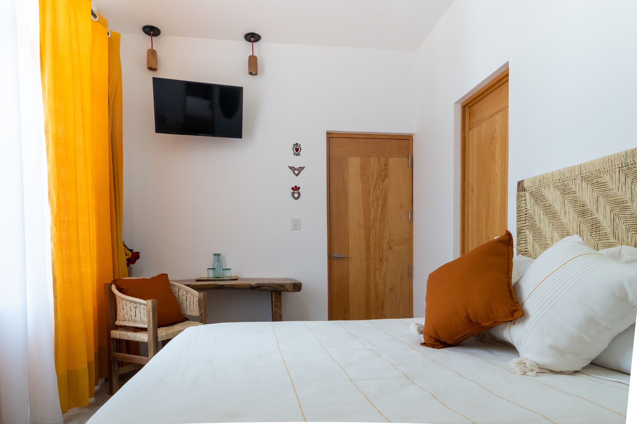 A bedroom with a bed, a desk, a chair, a television, and a door.