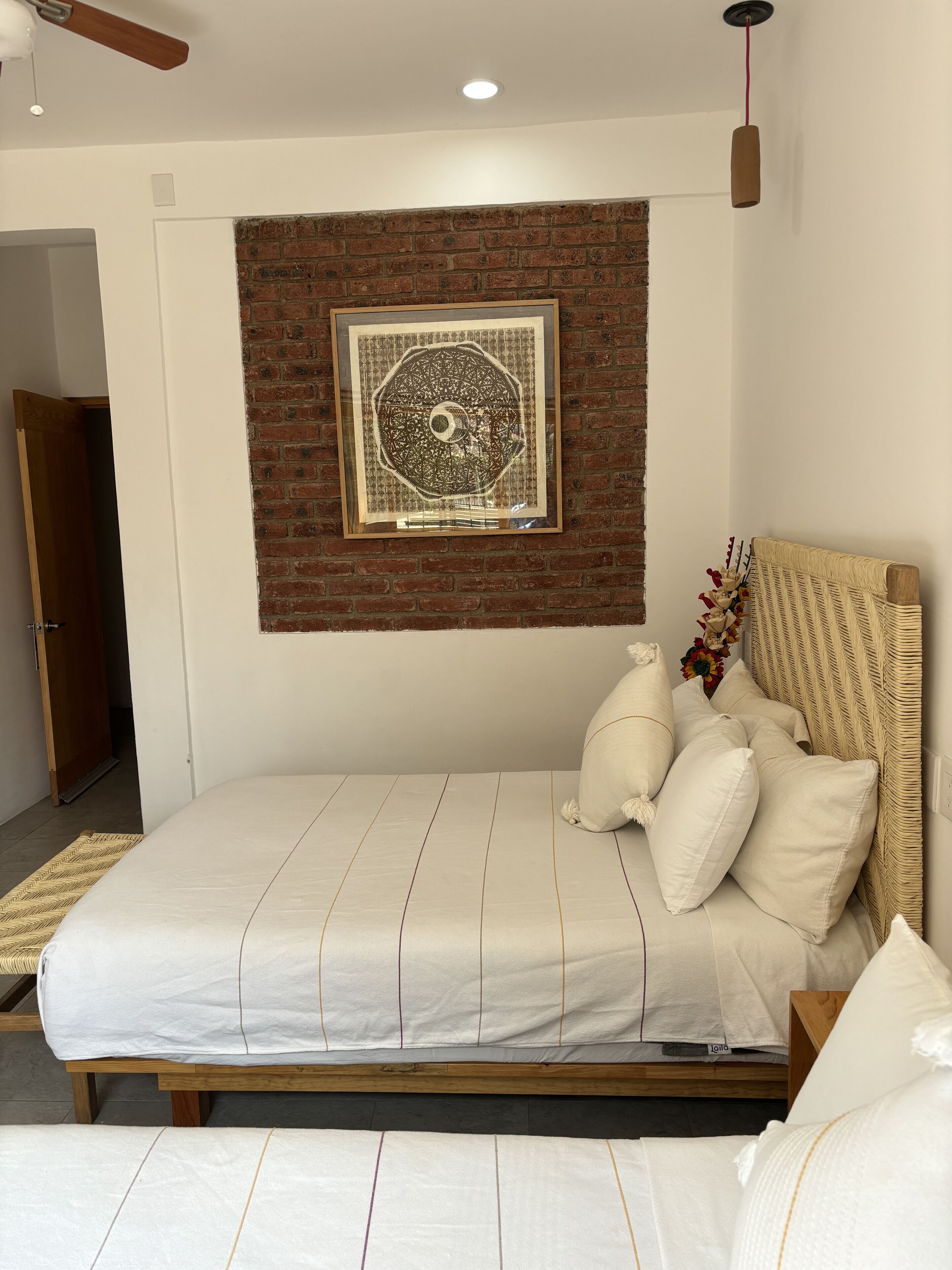 Un dormitorio con una cama de madera, una pared decorativa de ladrillo y una obra de arte enmarcada sobre la cama.