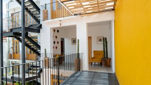 Un interno moderno con una scala, una parete gialla e un'area salotto con una poltrona e piante in vaso.