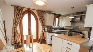 A modern kitchen with white cabinets, a wooden dining table, and a large window with curtains.