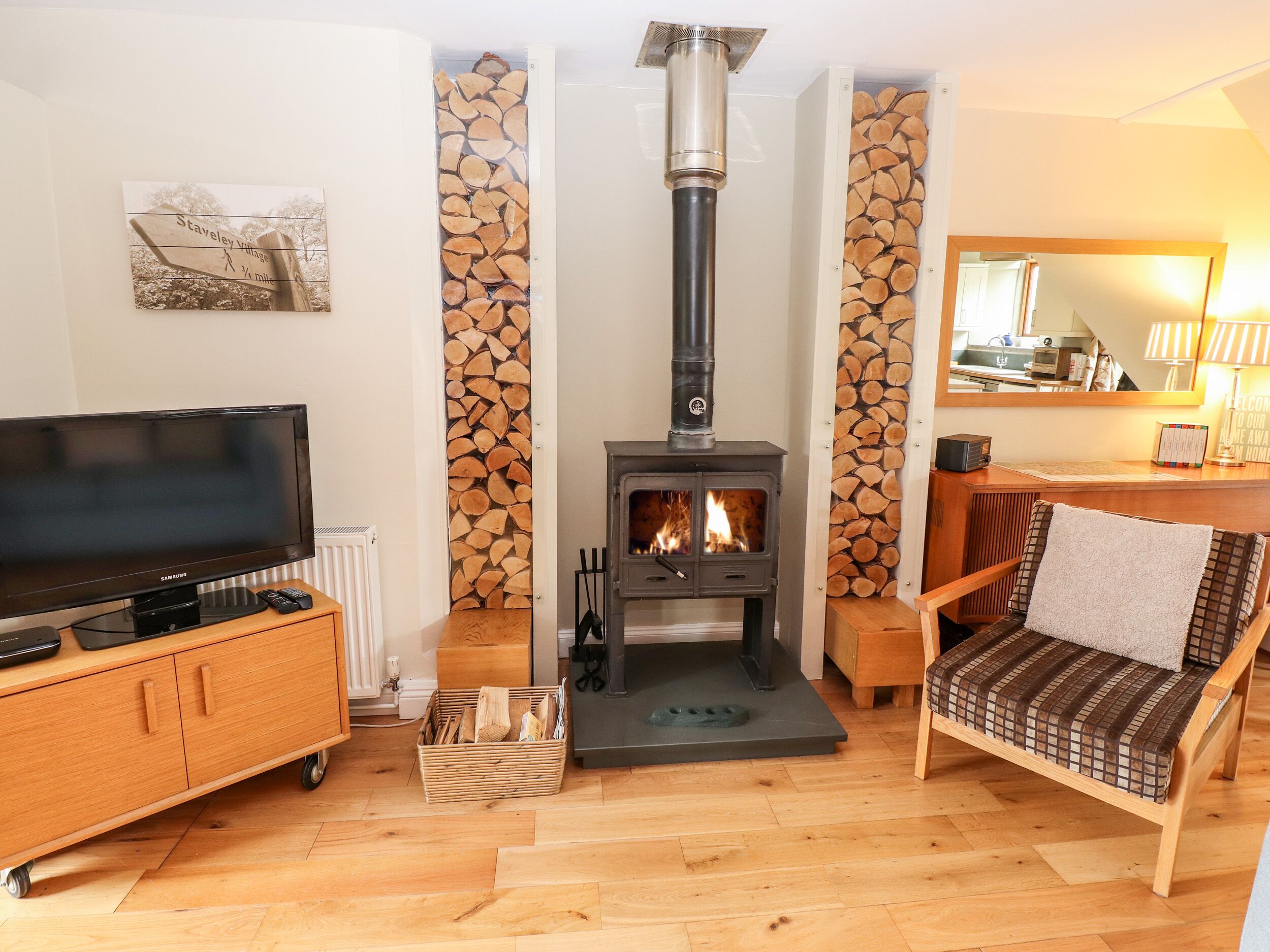 Una sala de estar con televisión, chimenea, sofá y un mueble de madera.