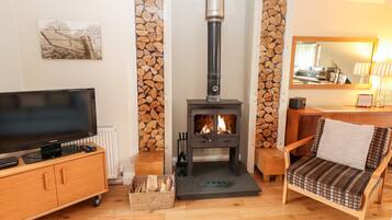 Una sala de estar con televisión, chimenea, sofá y un mueble de madera.