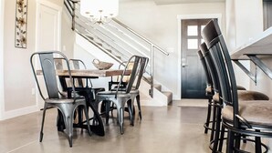 Een eetruimte met een tafel en stoelen, een kroonluchter en een trap.