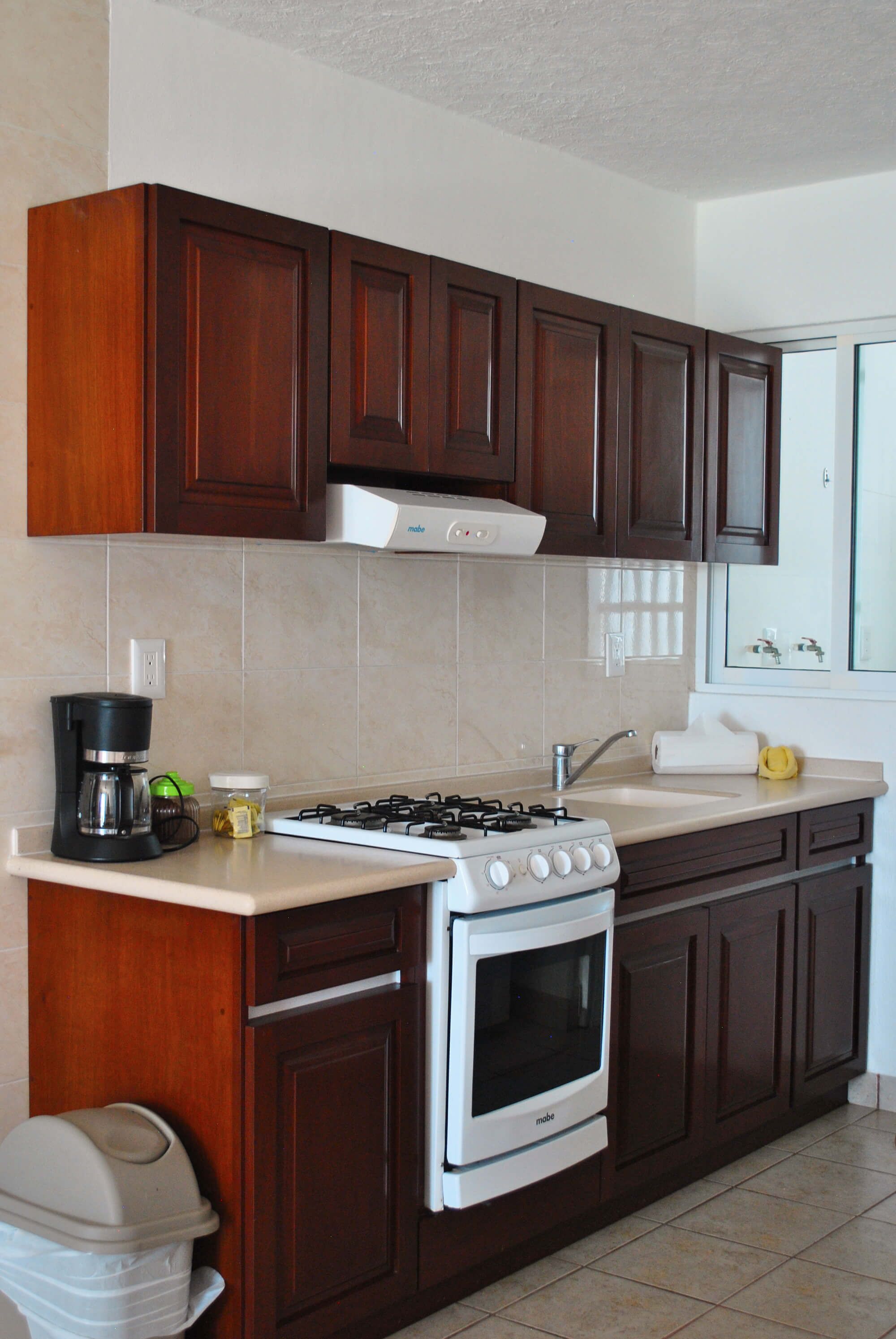 A kitchen with dark wooden cabinets, a white stove, and a coffee maker.
