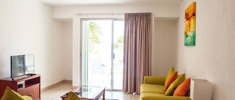 Una sala de estar con sofá, sillones, una mesa de centro, televisor y ventilador de techo.