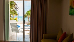Una sala de estar con un sofá, una mesa de vidrio y vistas a una piscina y palmeras.