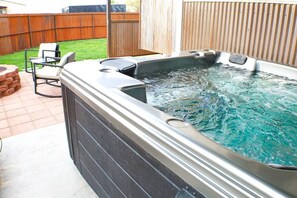 Una bañera de hidromasaje con un muelle de madera y sillas al fondo.