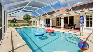 Una piscina interior con agua azul cristalina, dos anillos inflables y una pelota de playa.