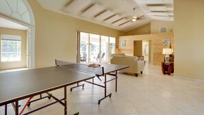 Una habitación amplia con mesa de ping pong, un sofá y una pared de madera.