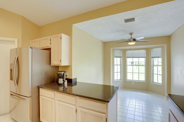 A kitchen with a refrigerator, cabinets, a countertop, and a ceiling fan.