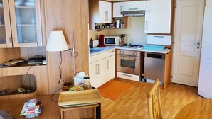Una cocina compacta con gabinetes de madera, un microondas, una estufa a gas y un lavavajillas.