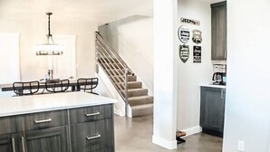 Eine moderne Küche mit dunklen Schränken, einer weißen Kochinsel und einer Treppe zu einer weiteren Ebene.