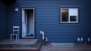 A house with a wooden deck, a white door, and a window with blinds.
