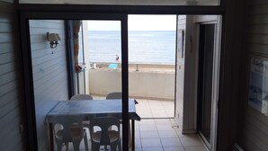 Un balcone con vista sulla spiaggia, un tavolo con sedie e una lampada a parete.