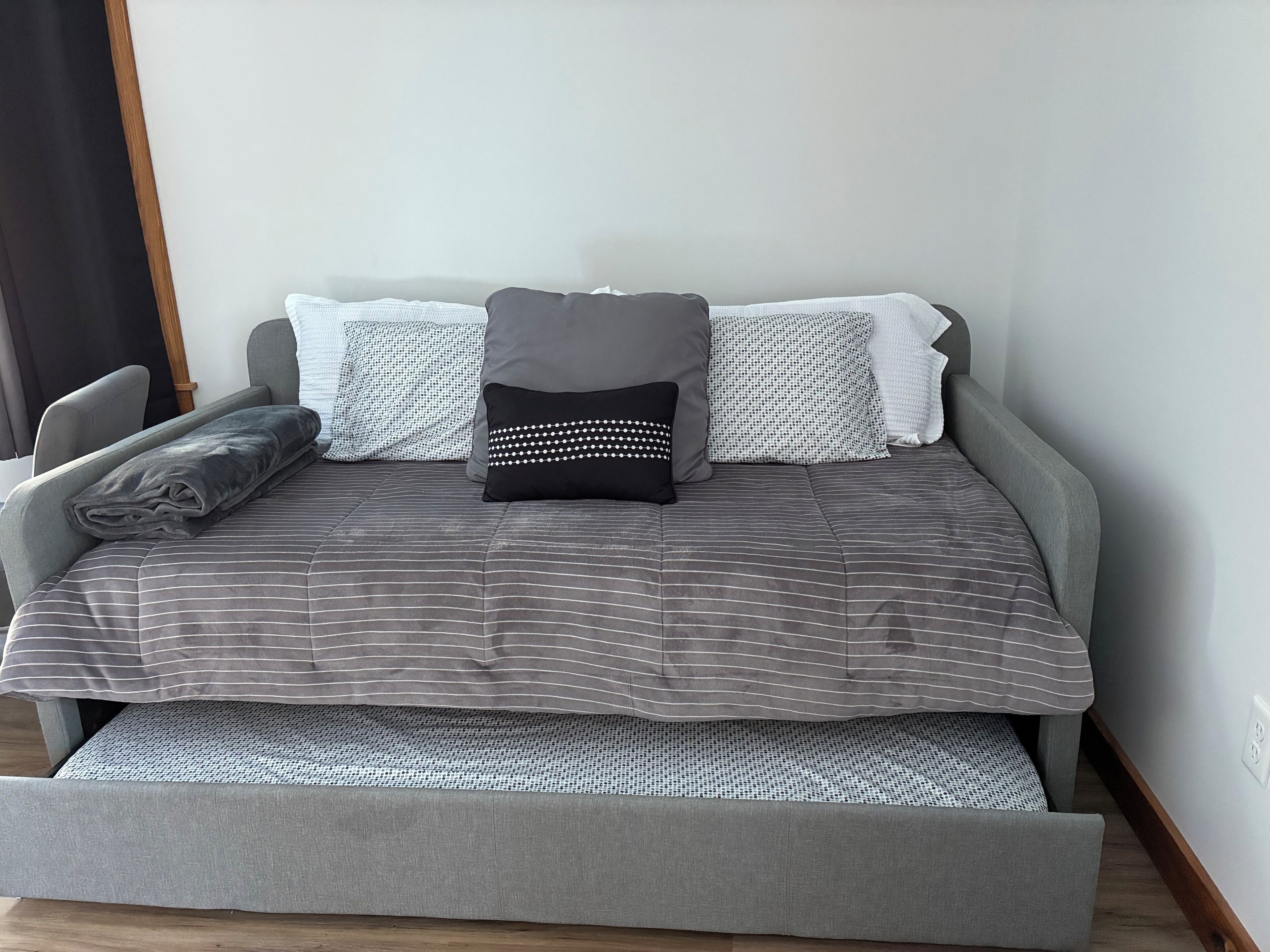 Una cama con cabecera y piecera tapizados en gris, y colchón a juego.
