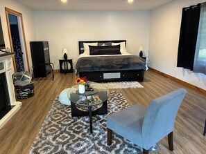 A bedroom with a bed, bedside tables, a chair, a small table with a vase of flowers, and a fireplace.