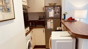 A compact kitchen with a washing machine, a refrigerator, and a microwave on a wooden countertop. - Large studio in Cannes-MON2 (CANNES)