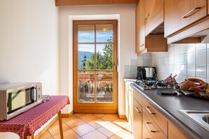 Une cuisine équipée d’un four à micro-ondes, d’une cuisinière et offrant une vue à travers une porte vitrée.