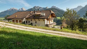 Une maison avec un toit en pente, un balcon et une vue sur les montagnes.