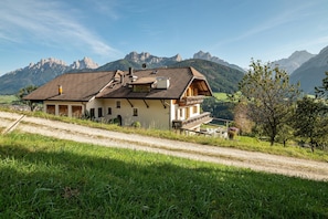 Une maison avec un toit en pente, un balcon et une vue sur les montagnes.