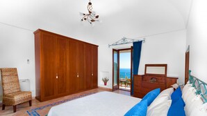 A bedroom with a bed, wardrobe, dresser, and a view of the sea through an open door. - Casa Sofia 310 steps (Positano)