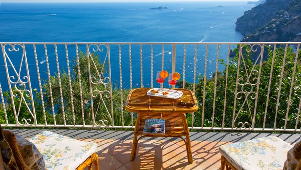 A balcony with a wicker table set for two, overlooking a coastal view. - Casa Sofia 310 steps (Positano)