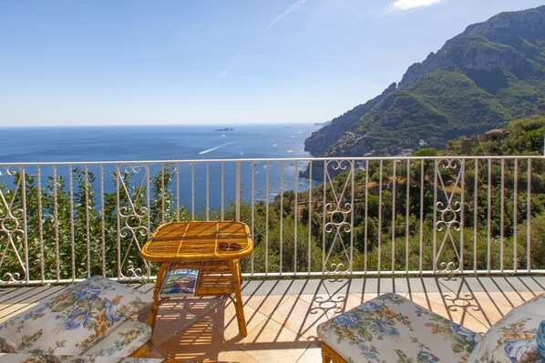 A balcony with a view of the sea, a wicker table, and floral cushions. - Casa Sofia 310 steps (Positano)