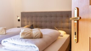 Ett hotellrum med en säng, en dörr av trä med ett handtag och en väggmonterad lampa.