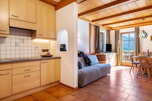 Una cocina con armarios de madera, salpicadero de azulejos y un comedor con sofá y mesa.
