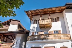 A multi-story building with wooden balconies, a tiled roof, and a clear blue sky.