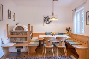 A cozy room with a wooden bench seating area, a table with chairs, and a ceiling fan.