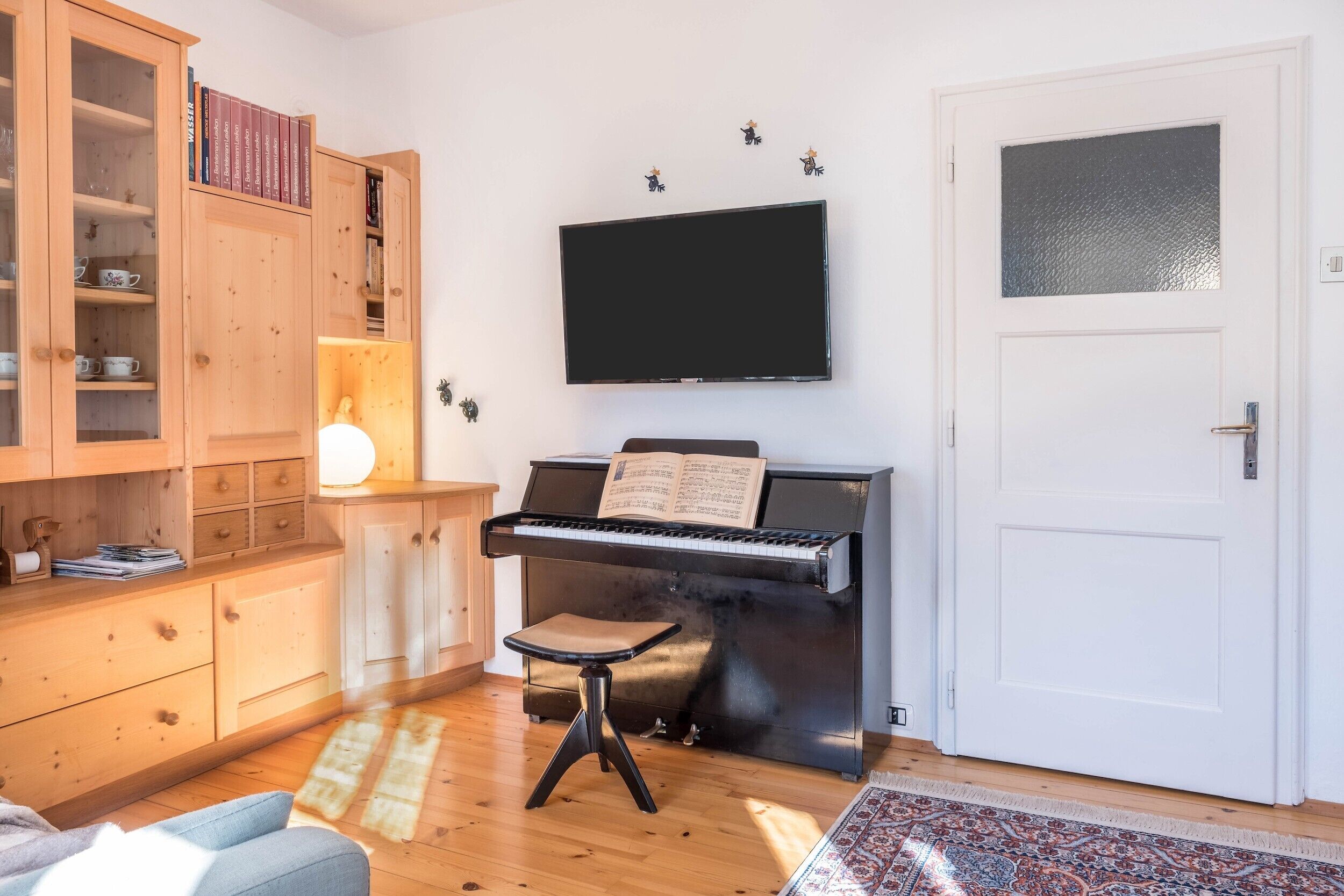 Un salon avec un piano, un téléviseur et une bibliothèque.