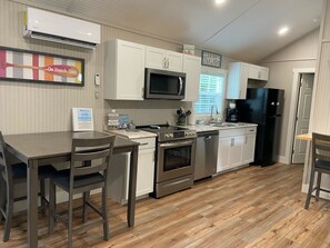 A modern kitchen with white cabinets, stainless steel appliances, and a wooden floor. - Cute cabin in nice quiet secluded area close to the water, The Coves Golf course (Afton)