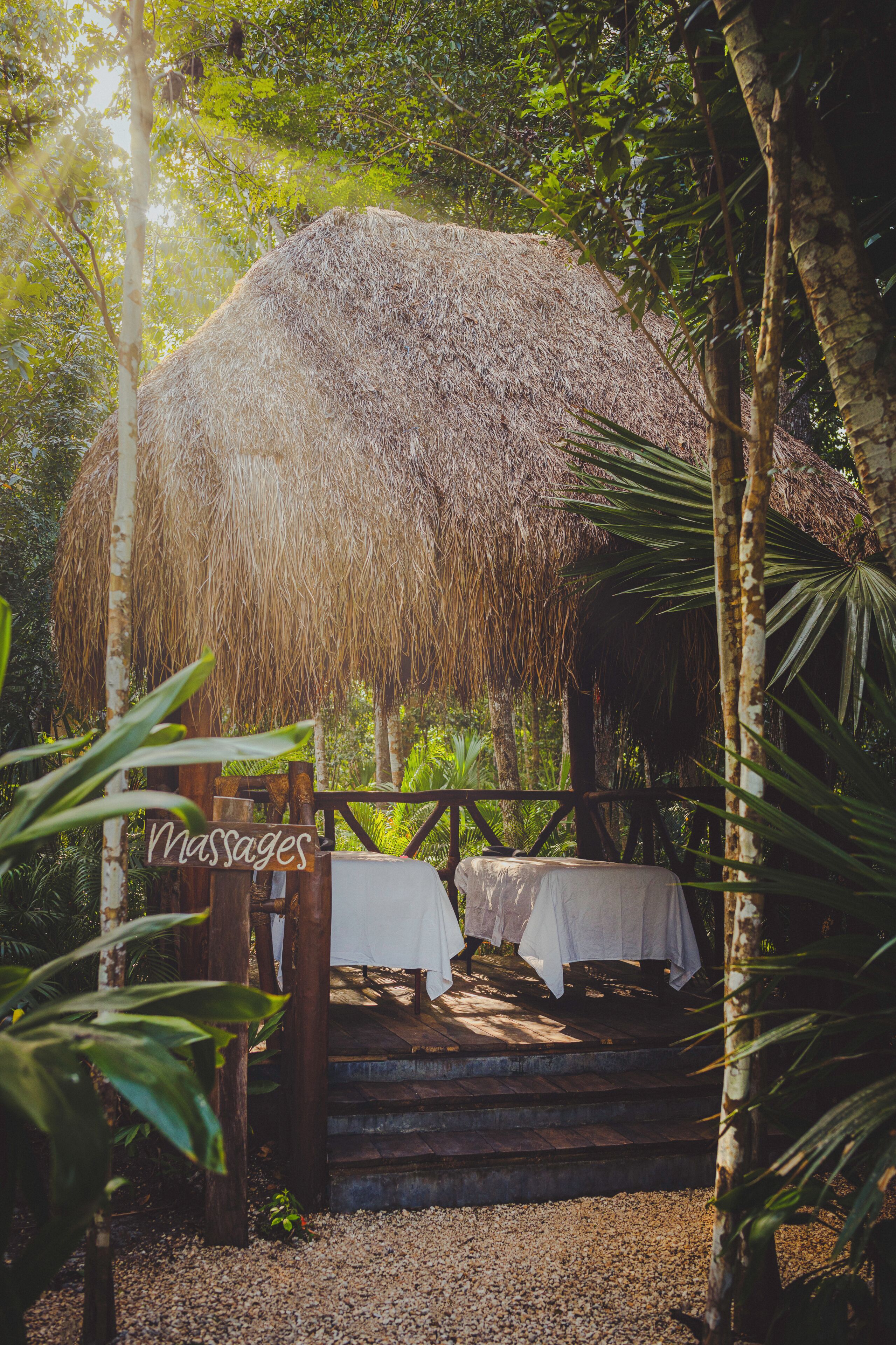 A thatched-roof structure with a wooden bench and a sign reading 'Massage'.