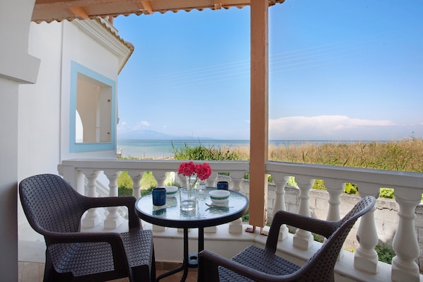 A balcony with a table, chairs, and a view of the beach.