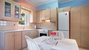 Une cuisine avec des meubles de rangement en bois, un réfrigérateur blanc et une table à manger dressée avec des assiettes et des couverts.