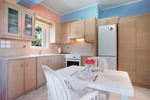 Una cocina con armarios de madera, un refrigerador blanco y una mesa de comedor con platos y cubiertos.