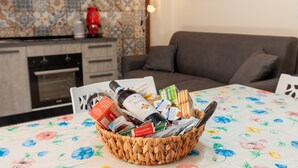 A wicker basket filled with various food items and a bottle on a table with a floral tablecloth.