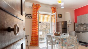 A kitchen with a refrigerator, a dining table with chairs, and a window with curtains.