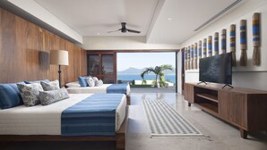 Un dormitorio moderno con una cama grande, televisión y vista al océano.